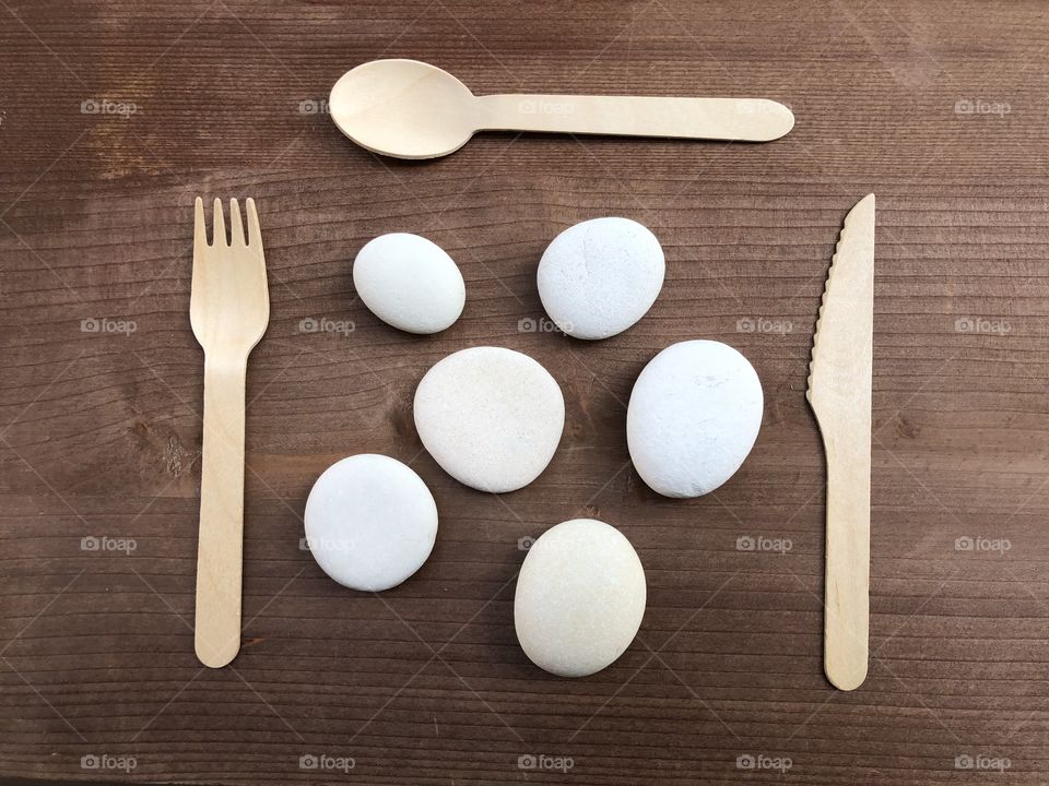 Meal time abstract concept with fork, spoon, knife and stones over wooden board