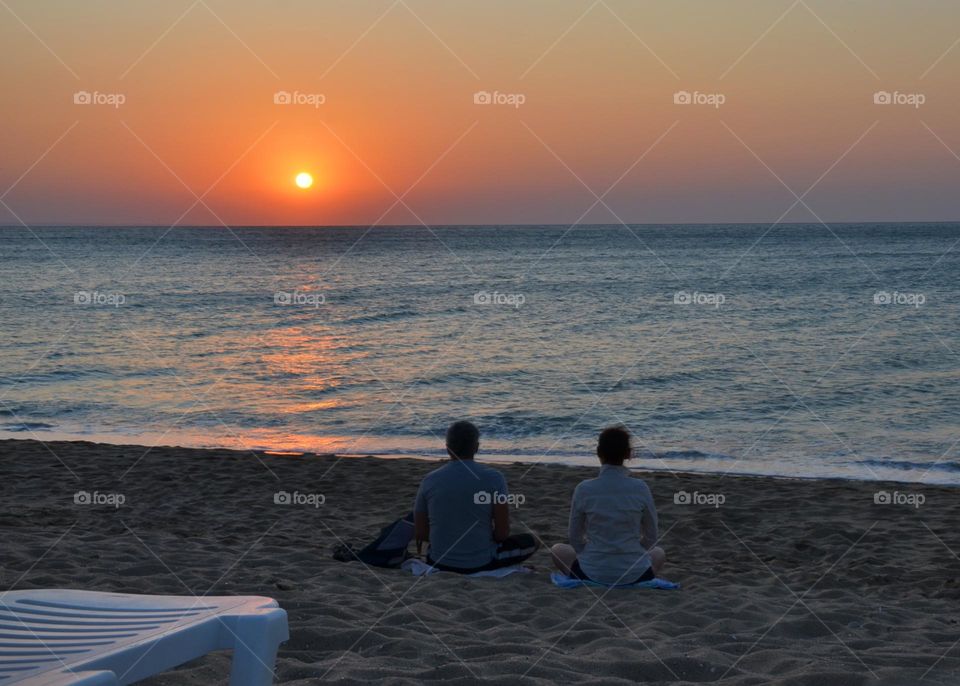 Couple Doing Yoga Outdoor at Sunrise on the Beach