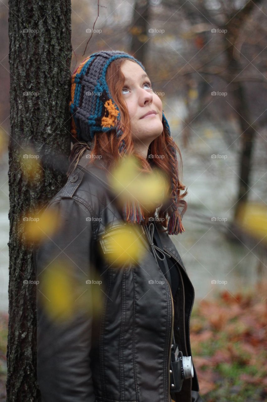 Teenage girl leaning on tree in forest