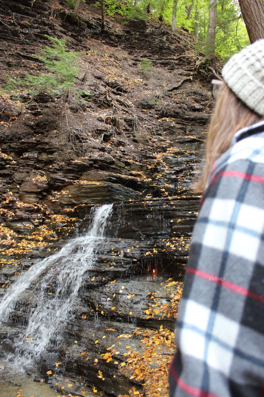 Young woman hiking in front of a waterfall in the autumn 