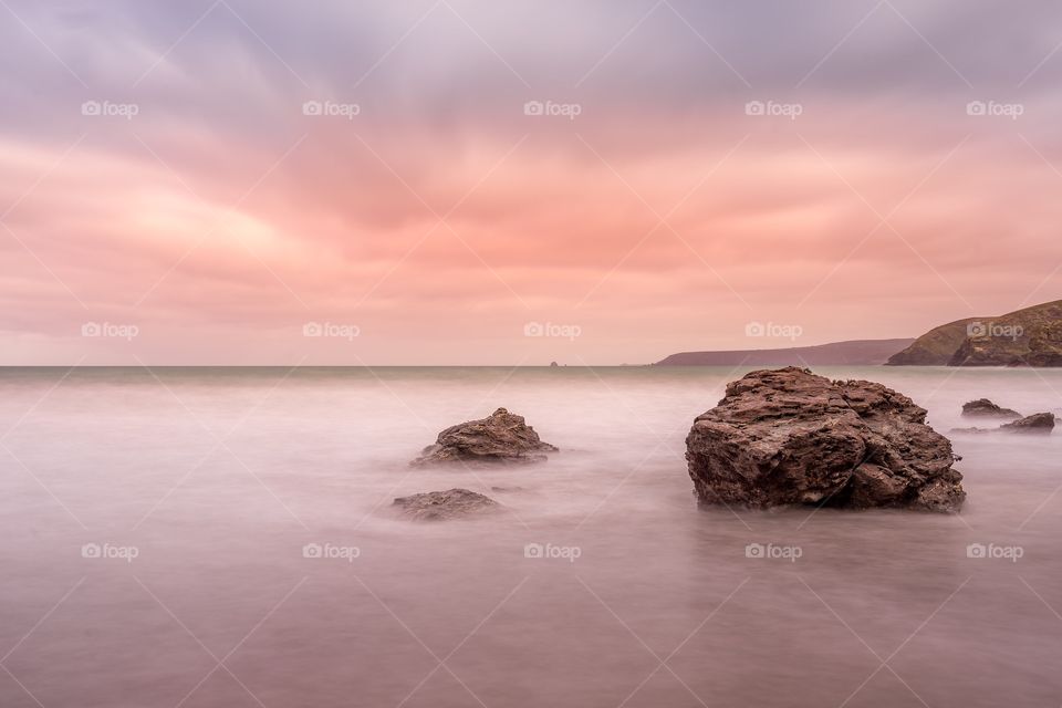 Sunset landscape at portreath beach in Cornwall. This is a long exposure sea landscape taken during an amazing sunset producing amazing colours in the sky which adds amazing detail to the clouds in the sky. In the background you can see the Coastline