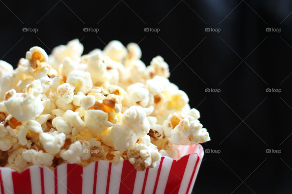 Popcorn in stripy box. Close-up of popcorn in a red and white striped box on a black background