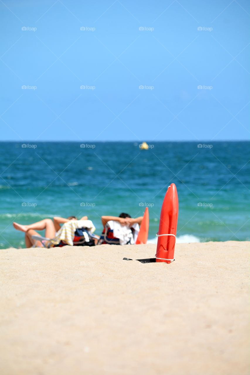 A young couple relaxing and lounging on the beach with a sandy beach in the foreground and tropical ocean water in the background