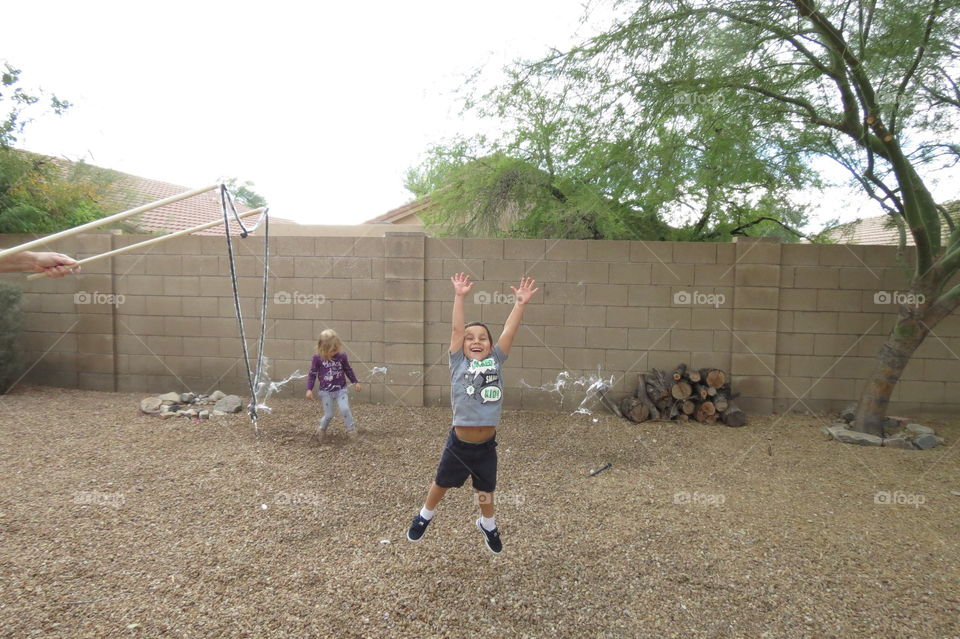 Little boy jumping up and popping a giant bubble.