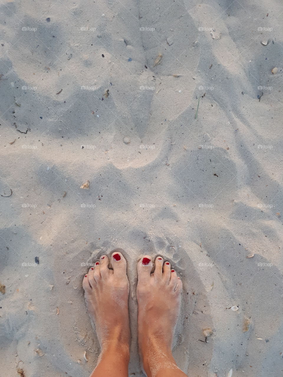 Woman's feet on the white sand