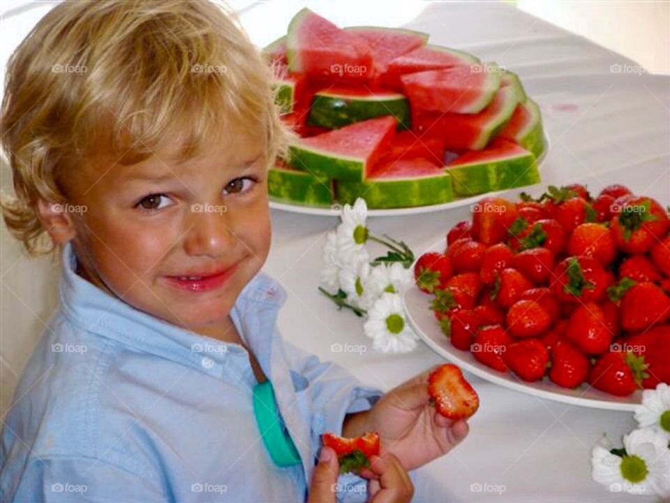 Cute boy gets ready to eat strawberries and watermelon 