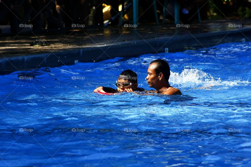 coach teaching a boy how to swim