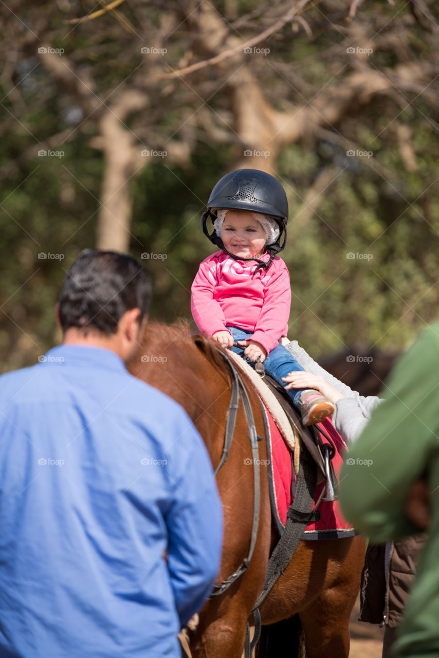 baby looking happily to her coach during her riding lesson