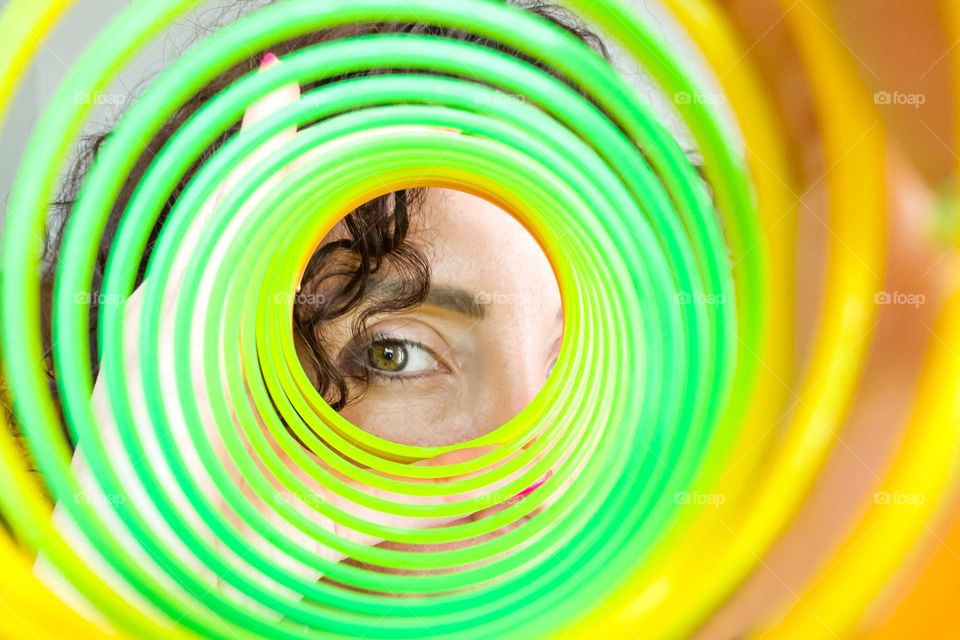 Circle, A Woman Looks through Rainbow Spring Toy