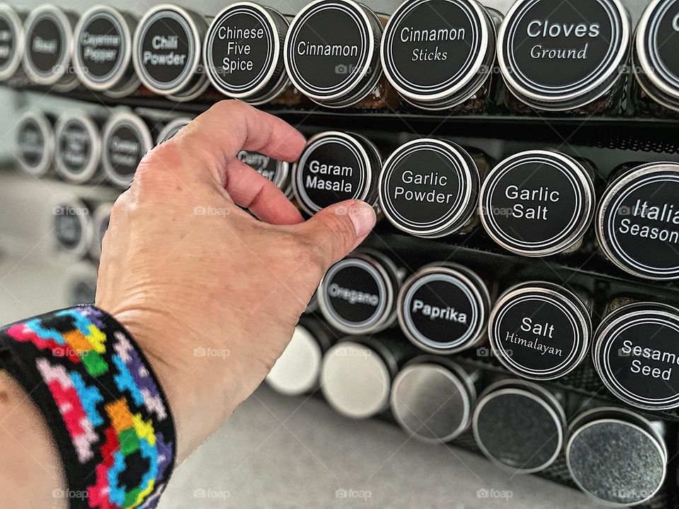 Cooking with spices, woman reaches for spices on rack, organizing your kitchen, woman get new spice rack, woman’s hand reaching for Garam Marsala 