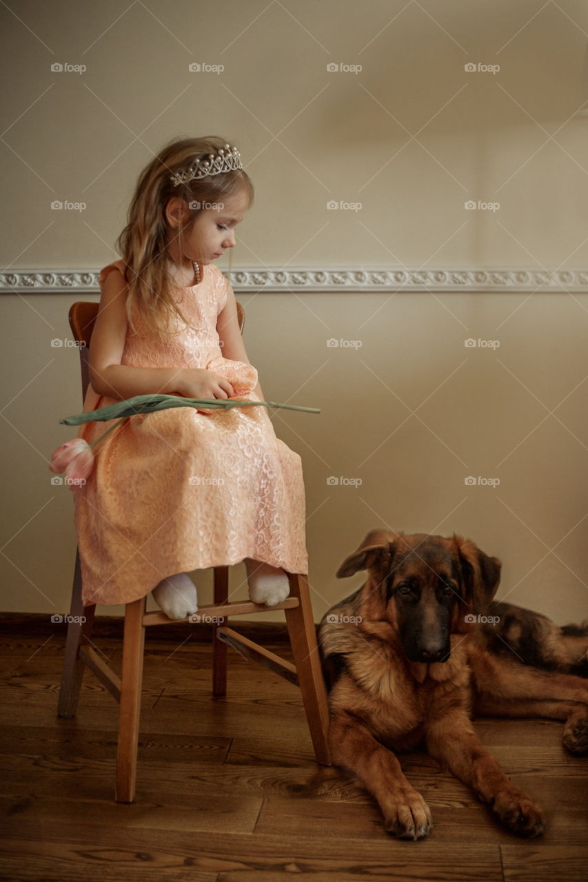 Vintage portrait of a beautiful little girl in pearl crown with tulip flower and German shepherd puppy 