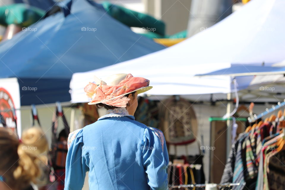 Woman wearing old fashioned period clothes and wearing floral bonnet at festival 