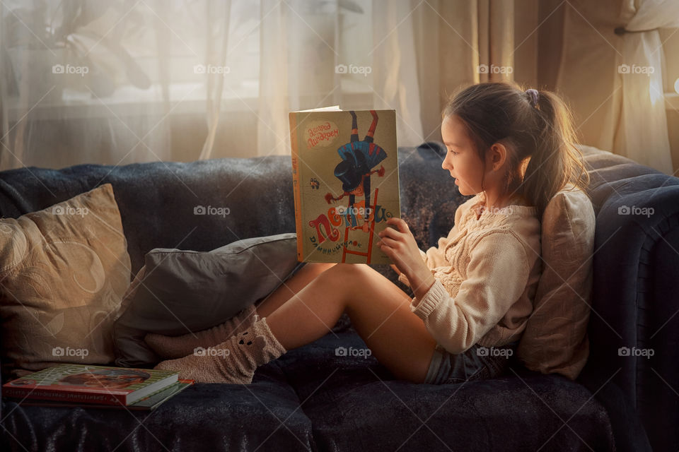 School girl reading the book at home