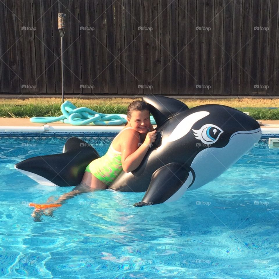 Girl floating on inflated orca, killer whale
