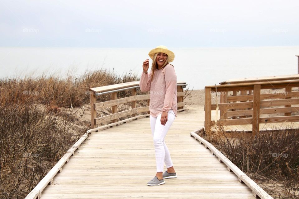 Female with pastel pink shirt with neutral beach background 