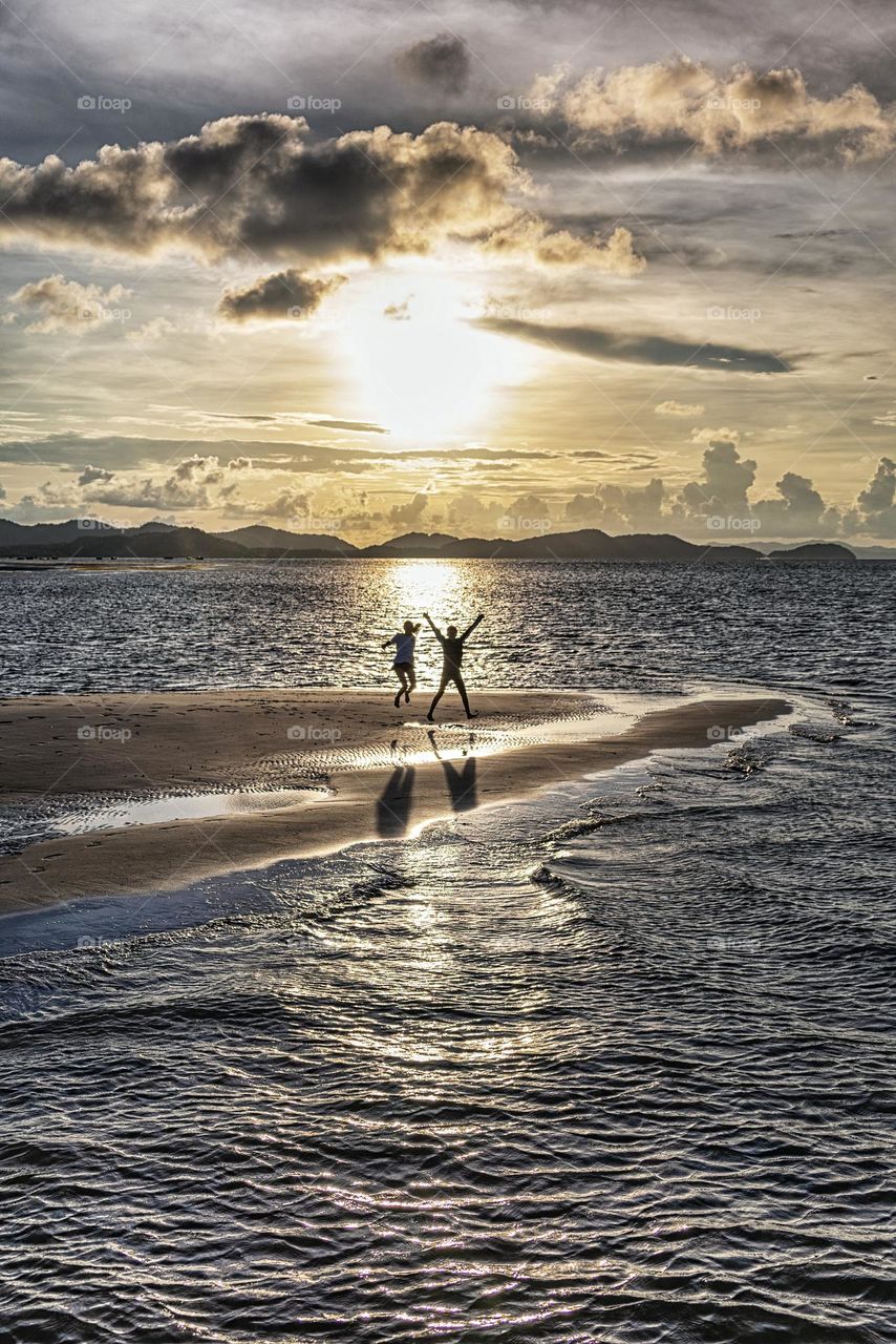 Silhouette of kids jump on sunset beach