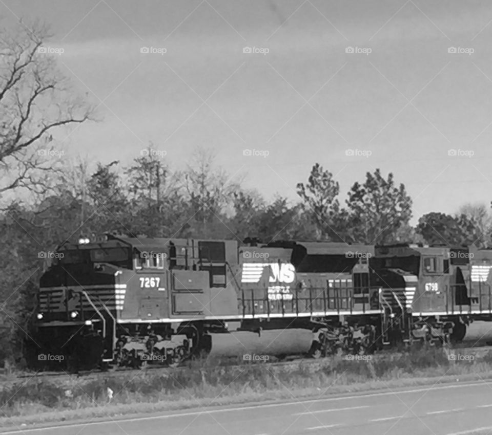 A black and white closeup of a train with engine coming down the track. 