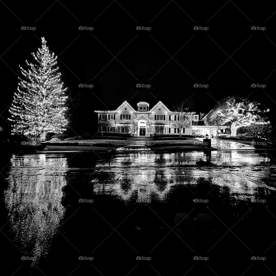 A mansion beautifully decorated with string lights that also included the trees on their front lawn. The evening rain paused for a few minutes and I was able to take this photo with the reflection from the wet street in front of this home.