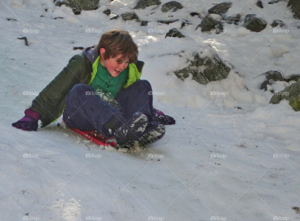 Boy Sledding In The Snow