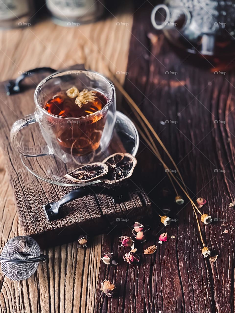 A cup of flower tea and some dried sliced lemon on a wooden board 