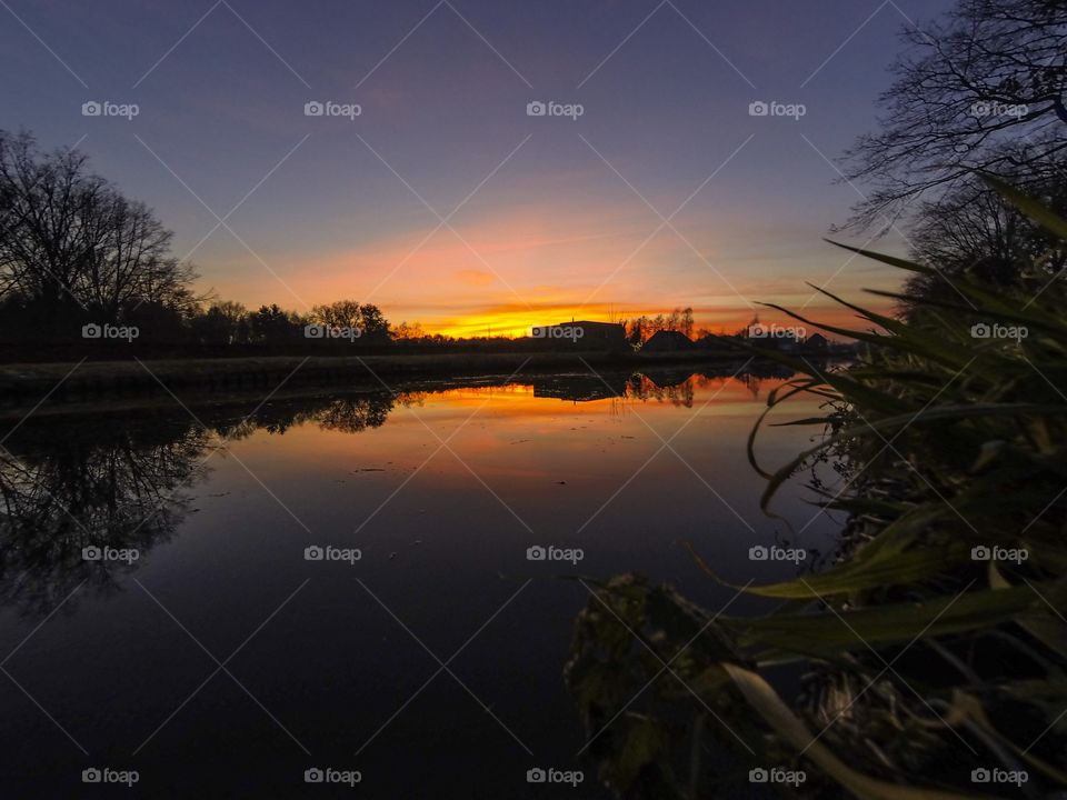 Countryside sunrise showing the colorful sky reflected in the water of the river 