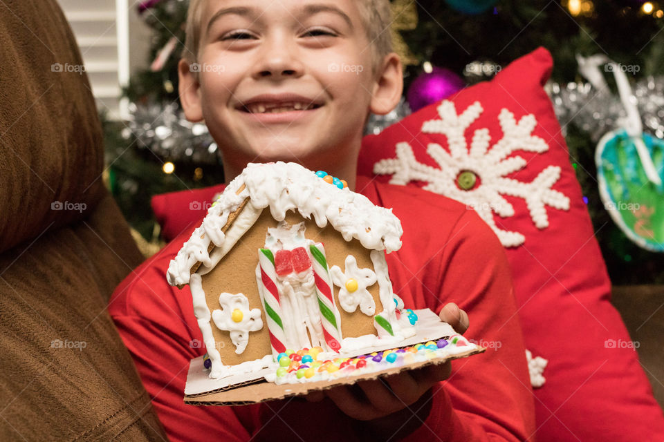 A boy proud of his gingerbread house