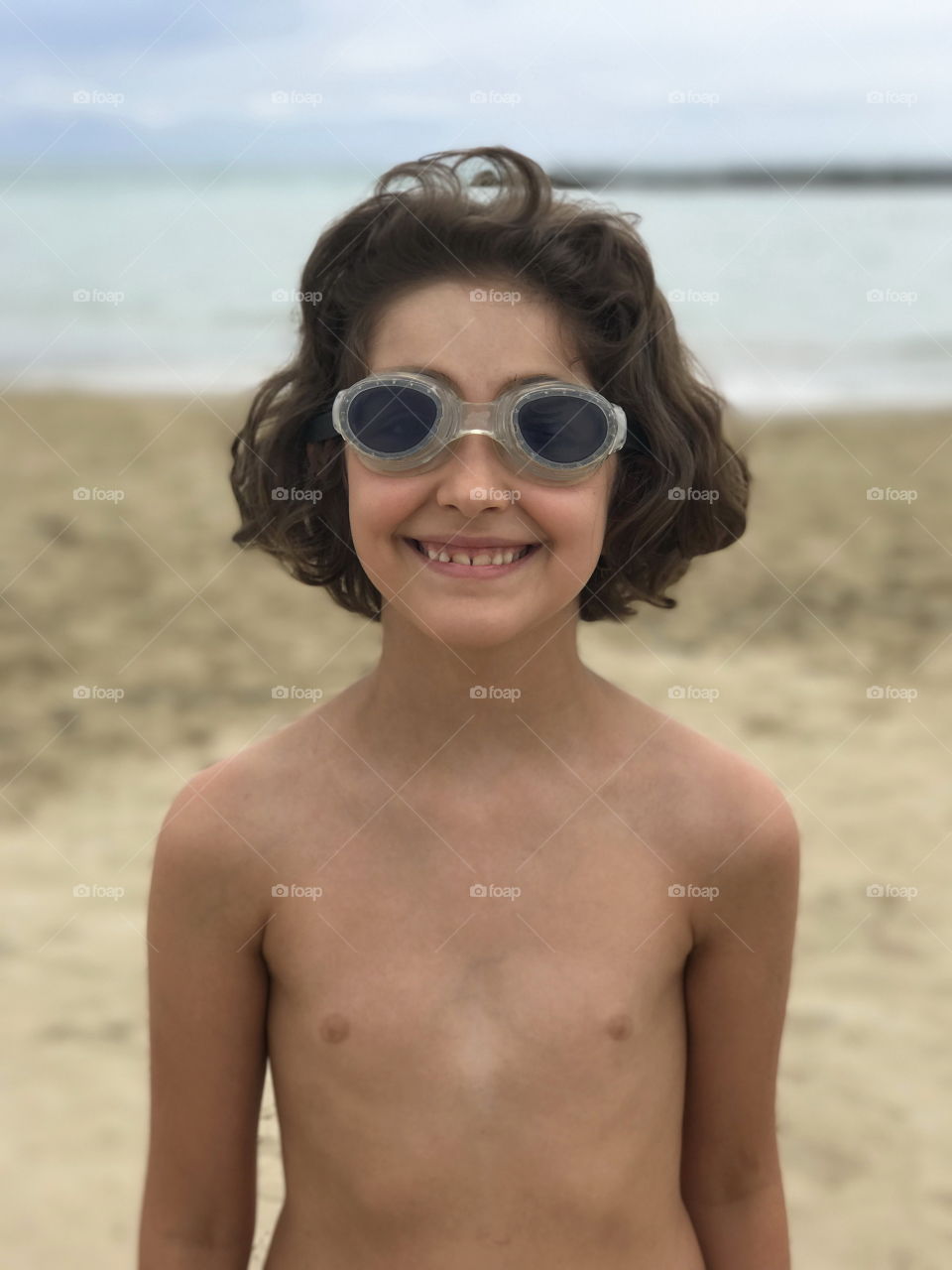 Happy eight years old girl with her pool goggles at the beach