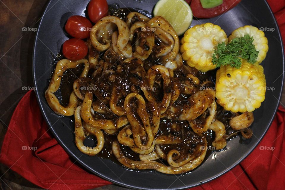 Close up Barbecue sauce flavored squid rings served on a black iron skillet — stock photo