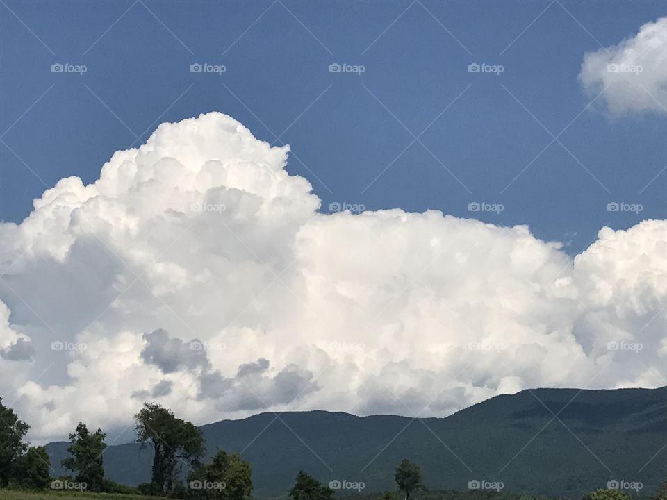 Immense white clouds billow over the distant blue hills