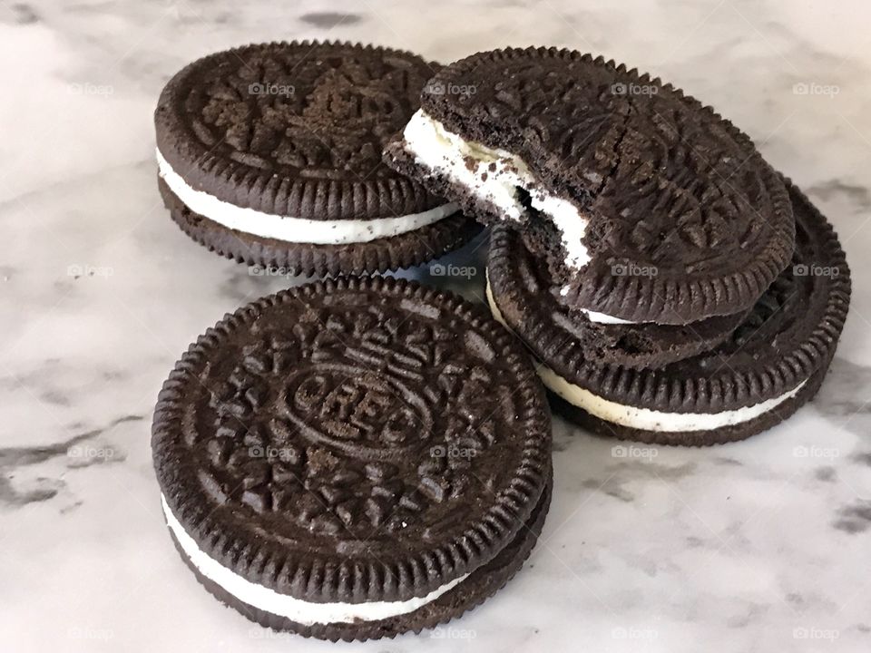 A pile of chocolate double stuffed Oreo cookies with a bike taking out of a cookie