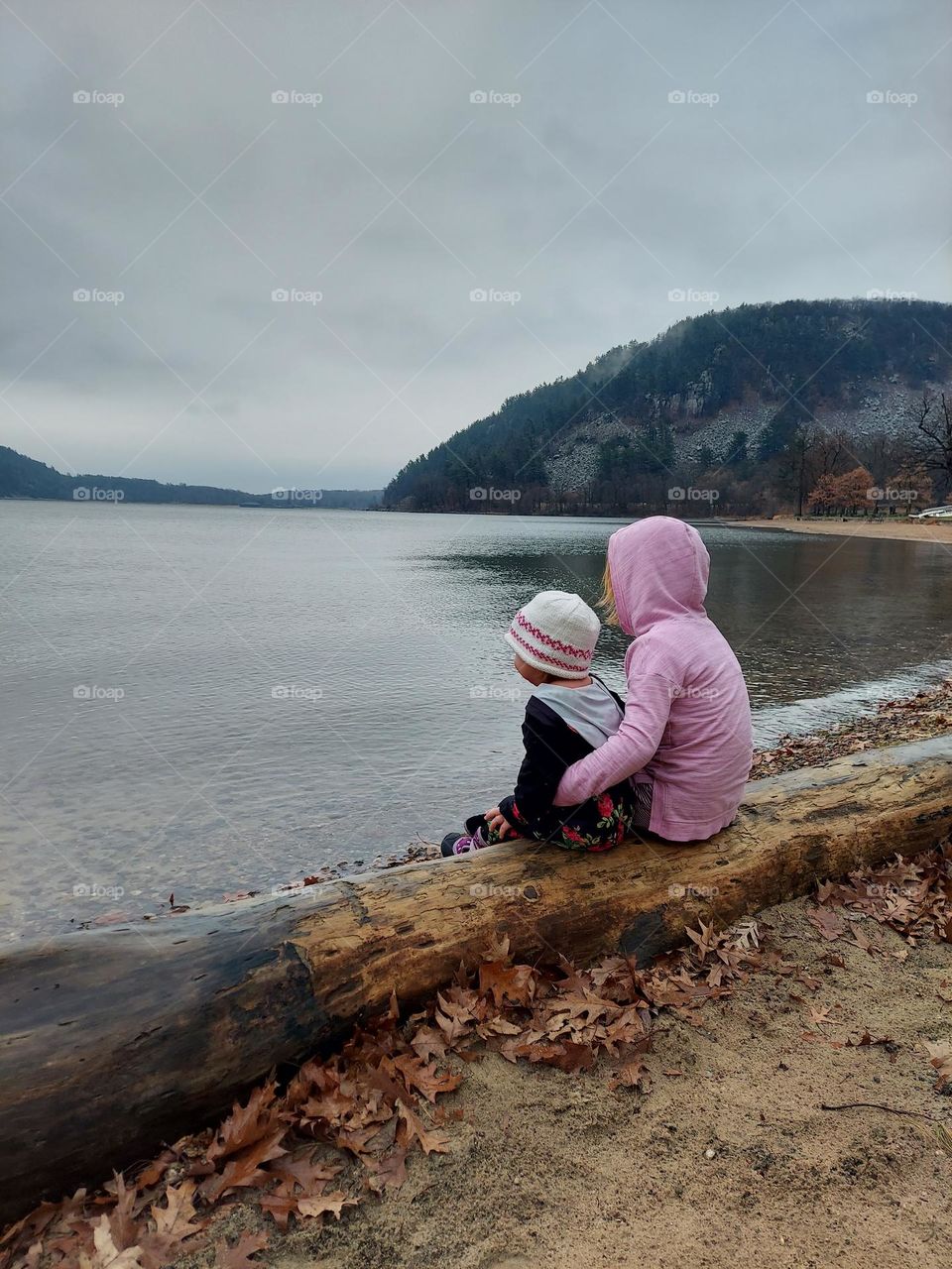 Sisters relaxing on a log and appreciating nature together.