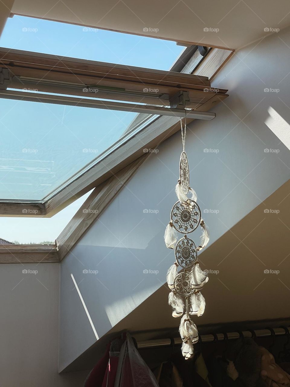 A dream catcher hanged on a skylight in a sunshine covered in shadows