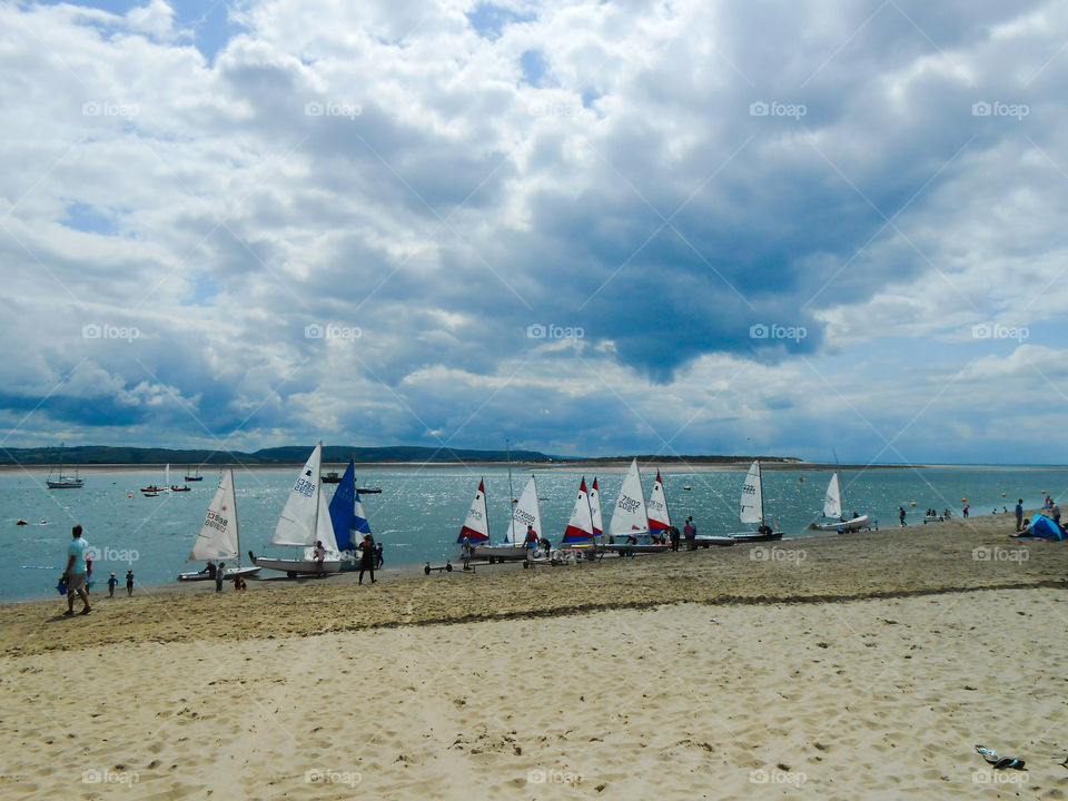 Sailing boats, sandy beach and dark clouds above