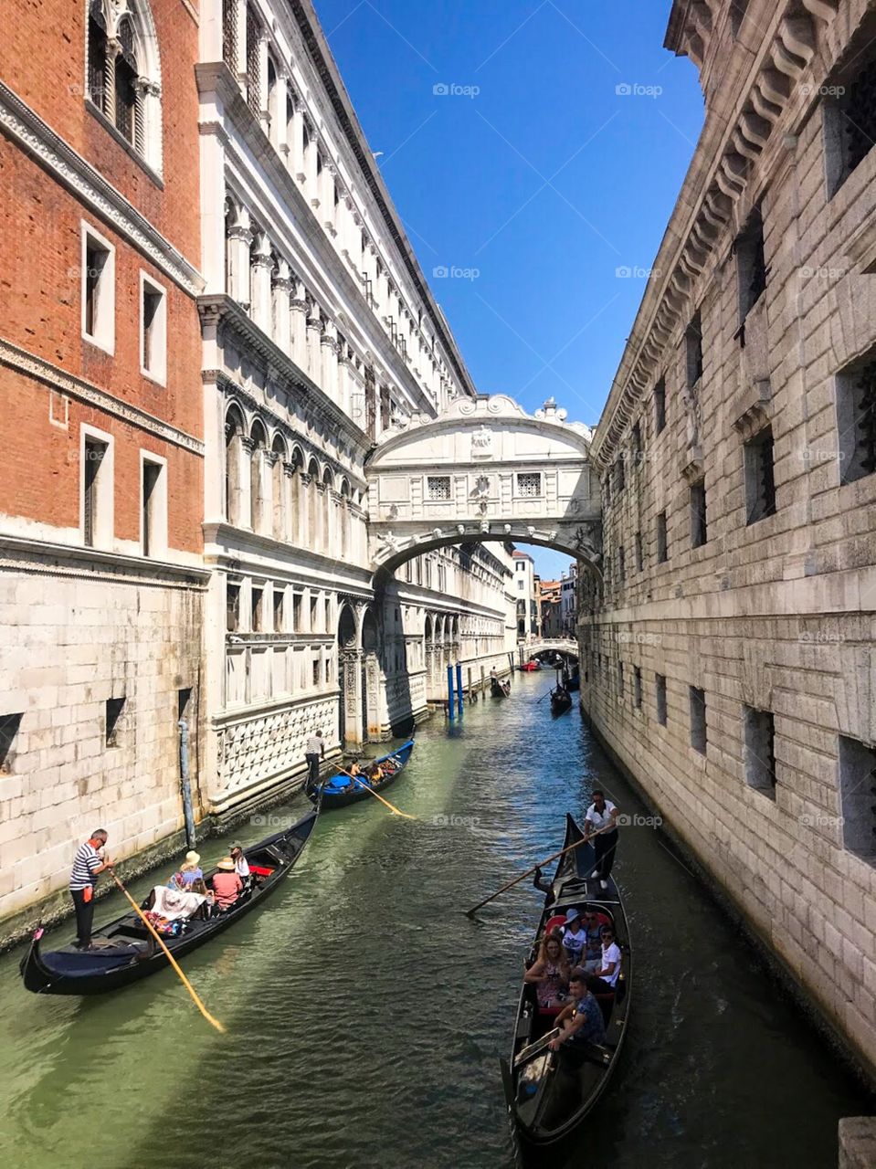 A small bridge connects the two sides of the building, there are very small windows, below is the canal, where the boats are carrying passengers. the view is wonderful