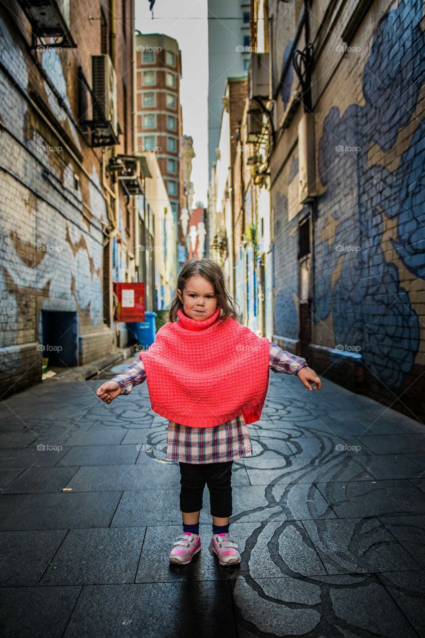 Little girl outstretching her arms standing in alley
