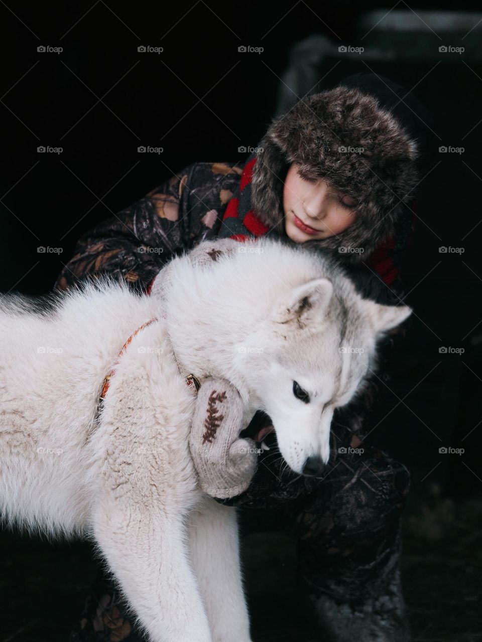Cute little boy with husky dog in winter cold day on dark background, portrait of child 