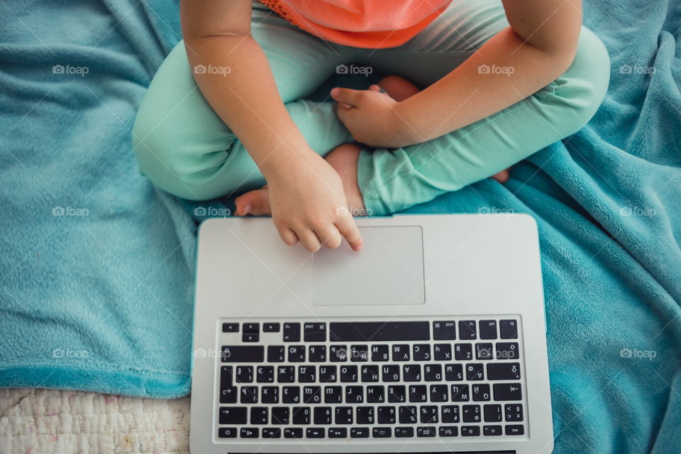 Little sisters with gadgets(laptop and tablet) in the bed.