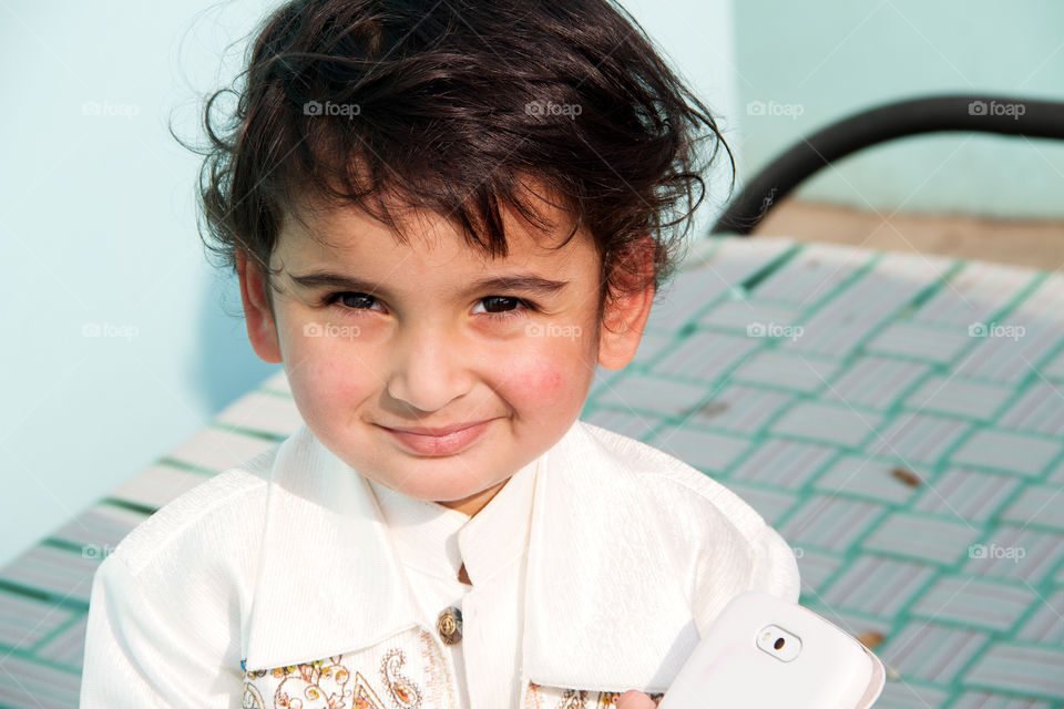 Cute Indian boy with white clothes sitting outdoors during winter