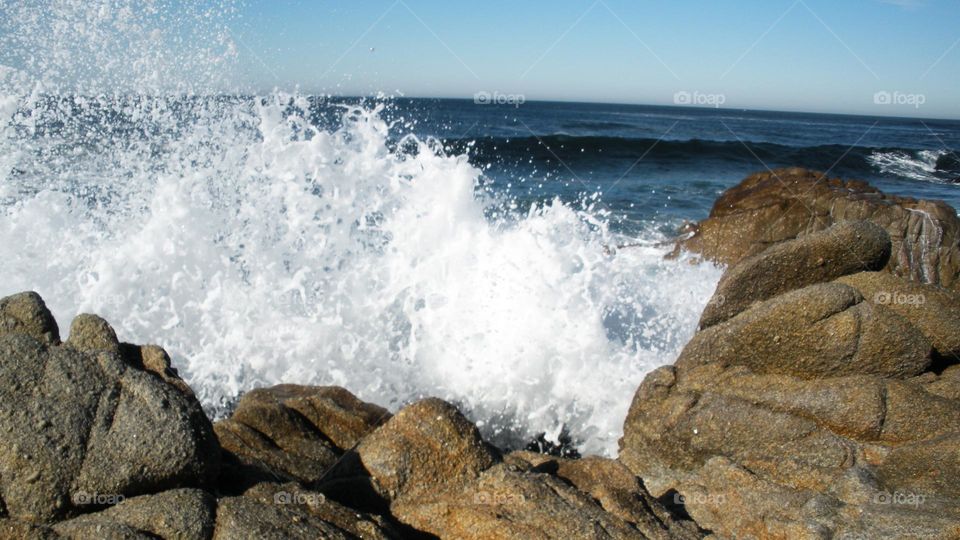 Foamy ocean waves breaking on rocks in Coastal California