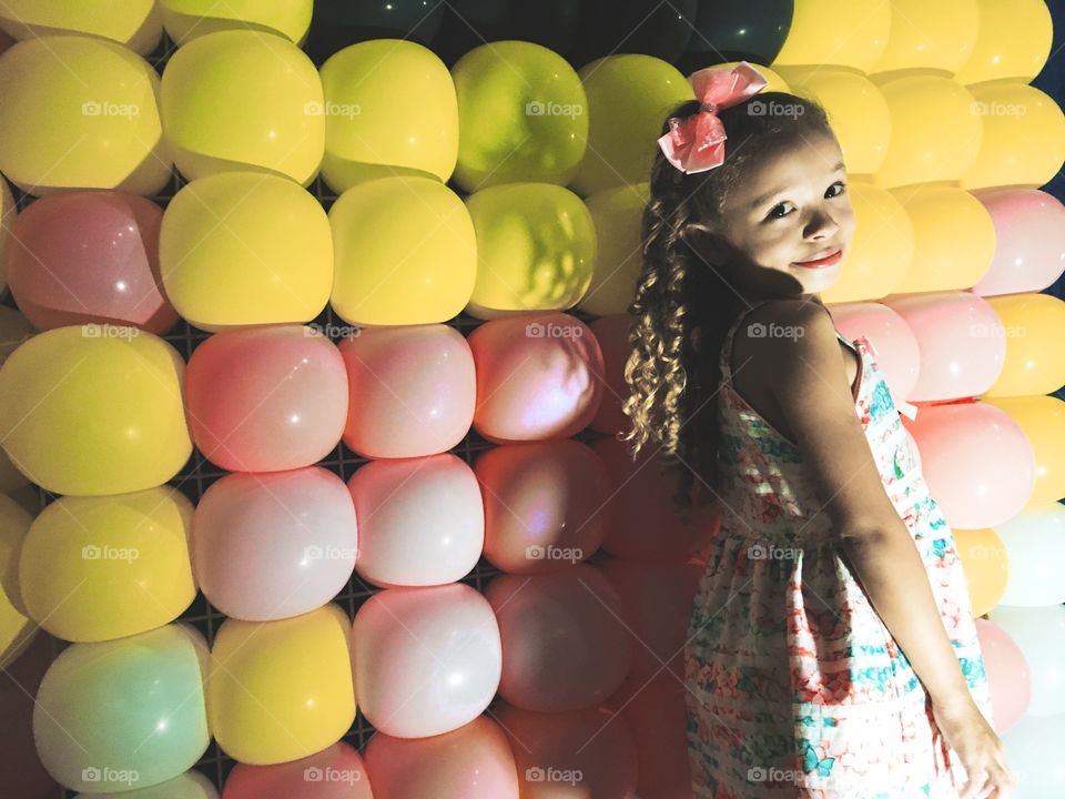 Little girl standing in front of balloon wall