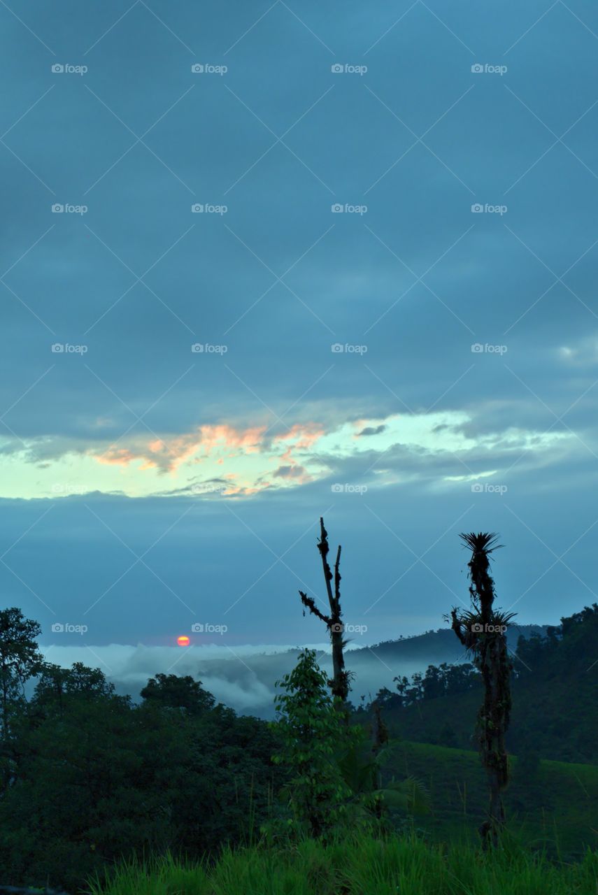 Sunset with sky blue sky and are on the horizon in the middle of the mountain