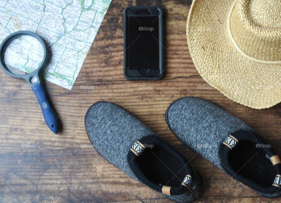 Flat lay, travel planning, shoes, hat, map, phone, magnifying glass 