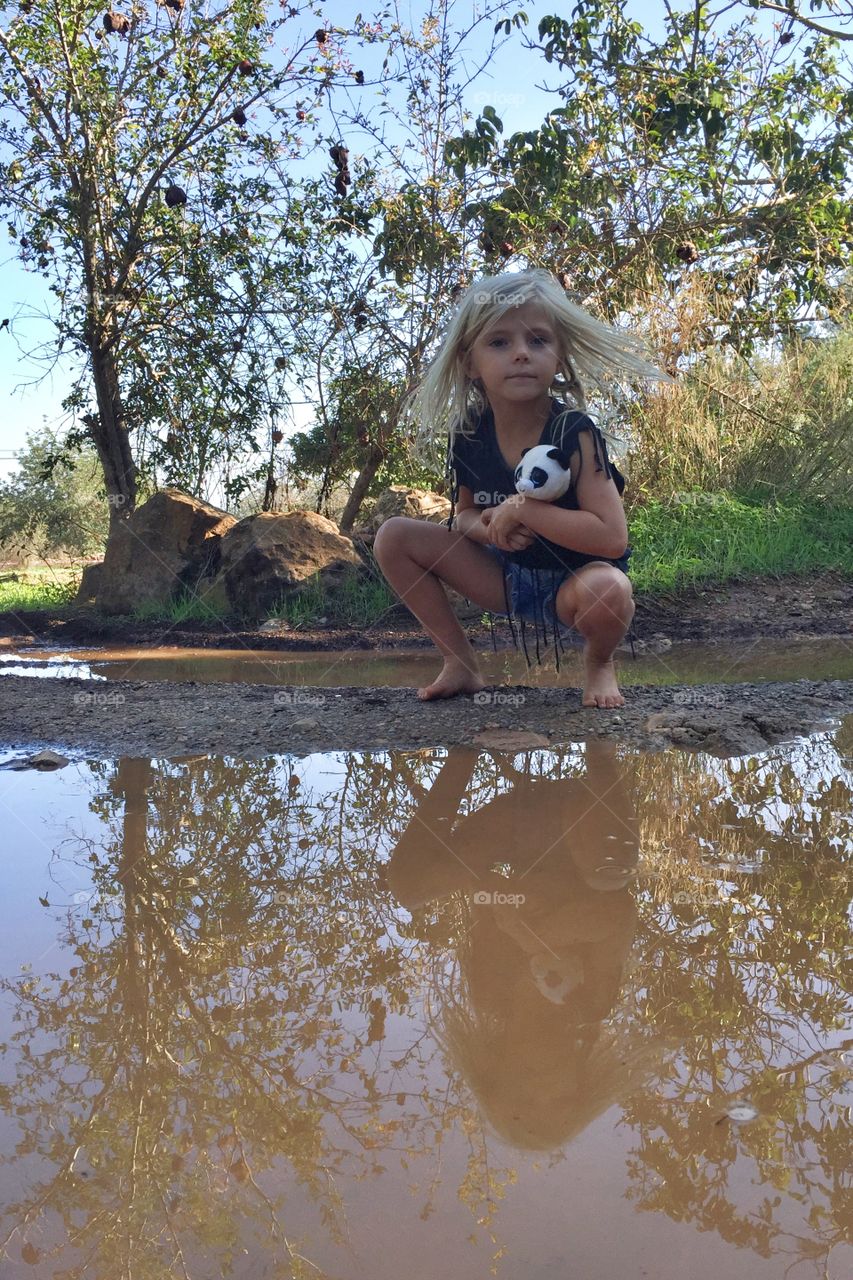 Girl sitting by a puddle