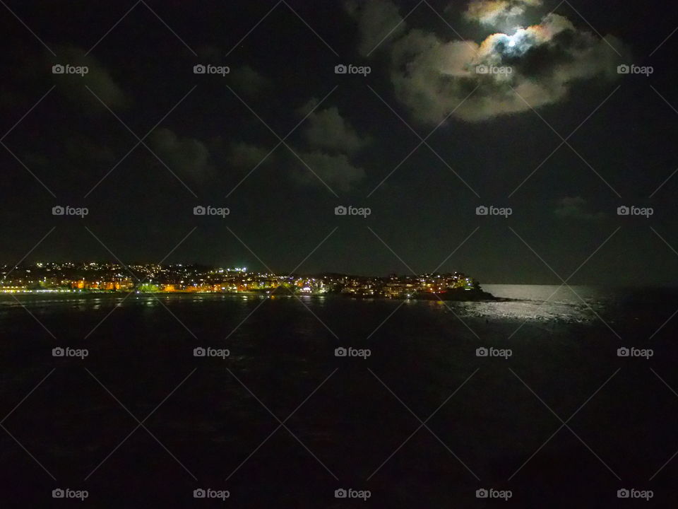 Bondi beach overview at night with moon peaking through the clouds