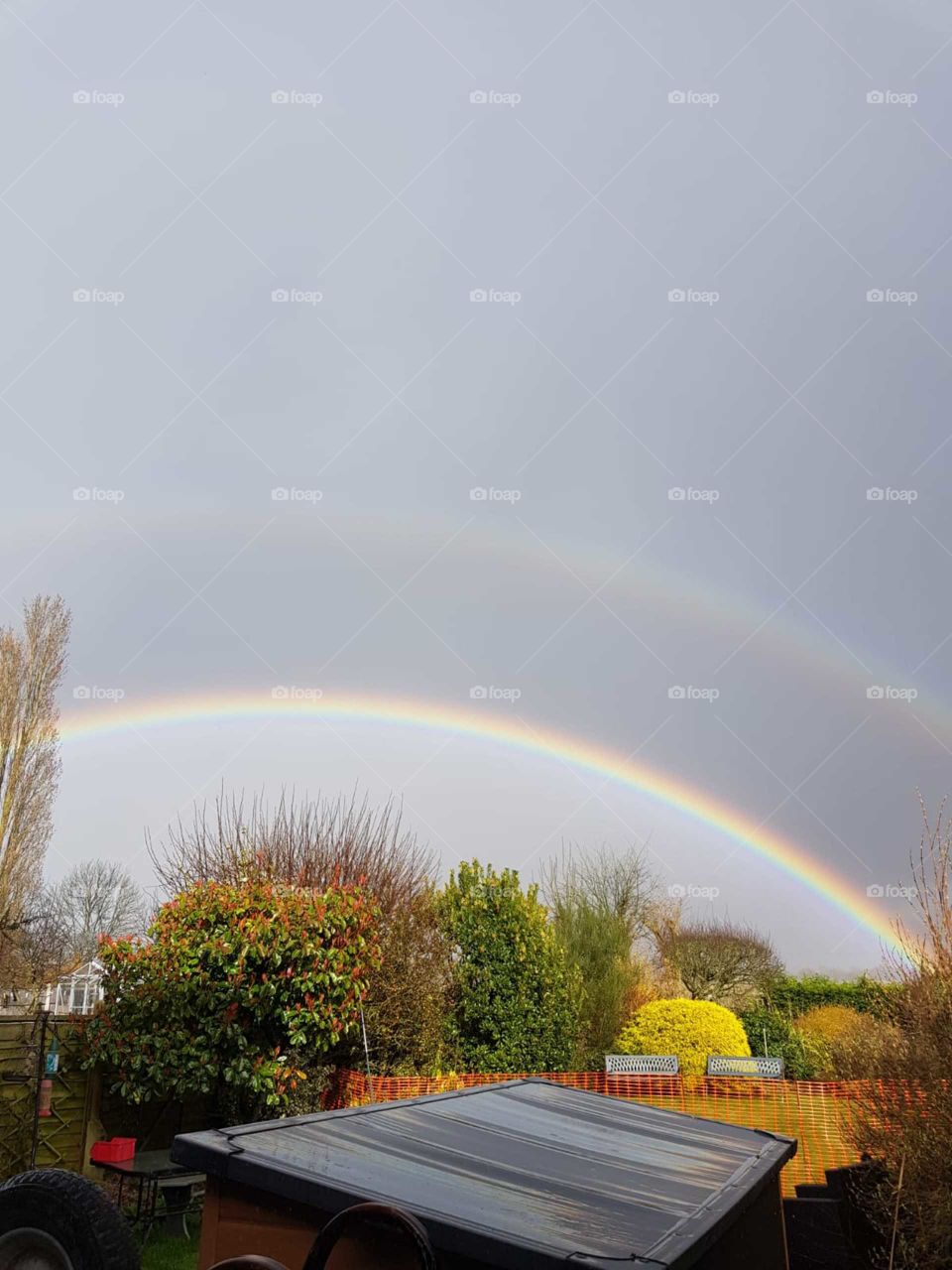 A very beautiful double rainbow present within dark skies.