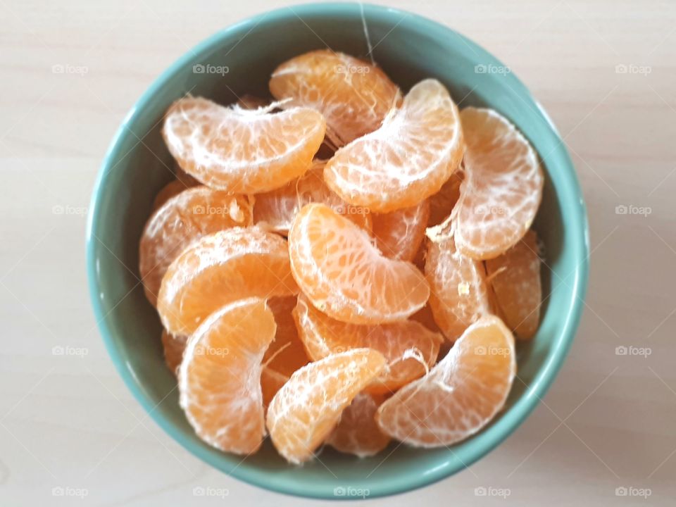 Fresh orange fruit peeled in green bowl on wooden table