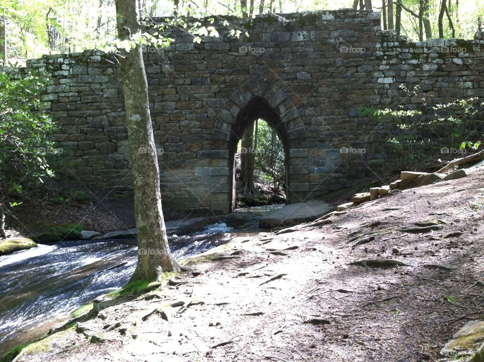 Historic stone bridge over stream on a sunny morning.