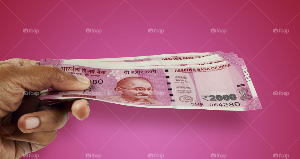 Indian money rupee 2000 currency notes in purple background in a hand