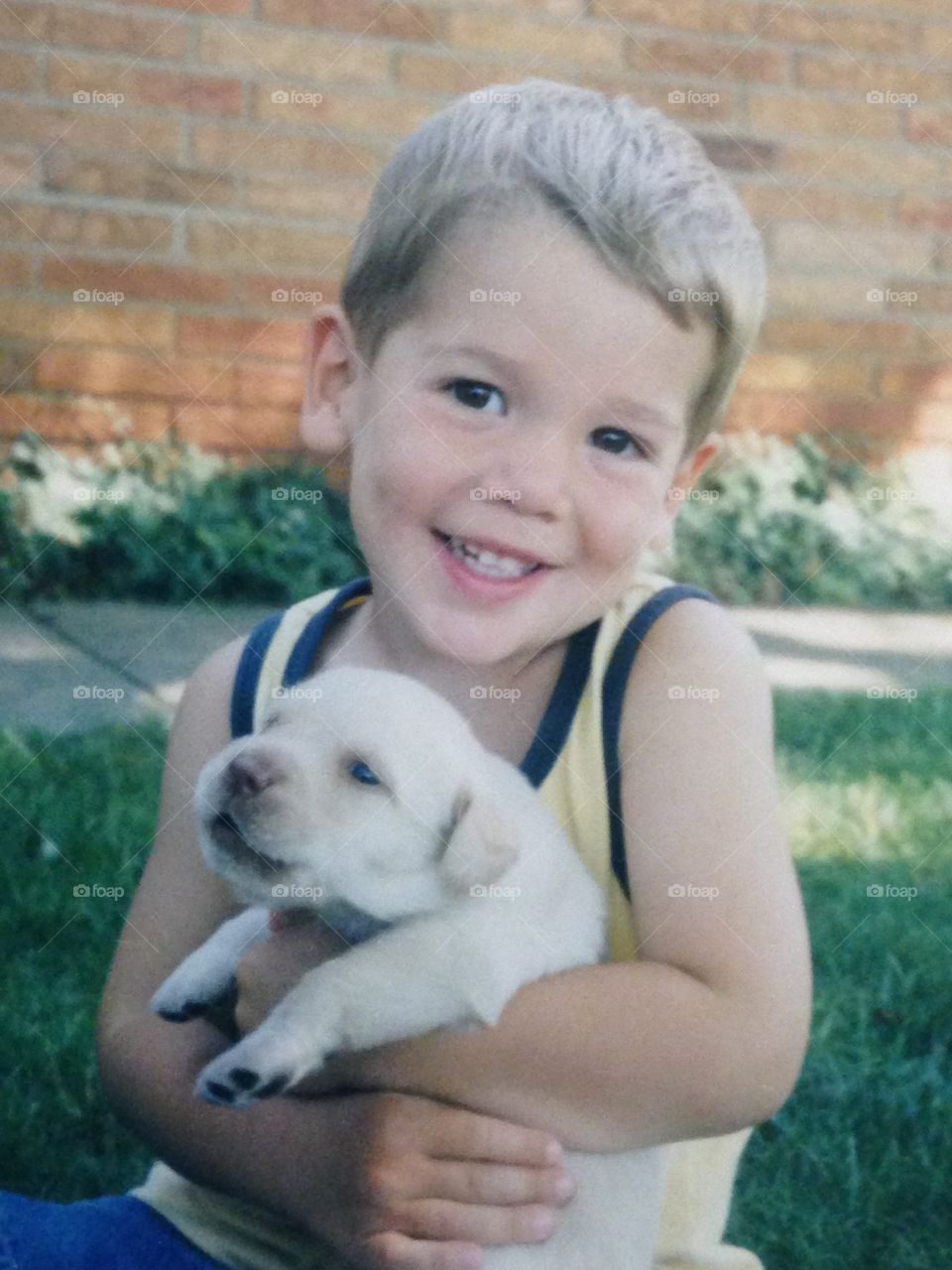 Adorable boy holding cute yellow puppy