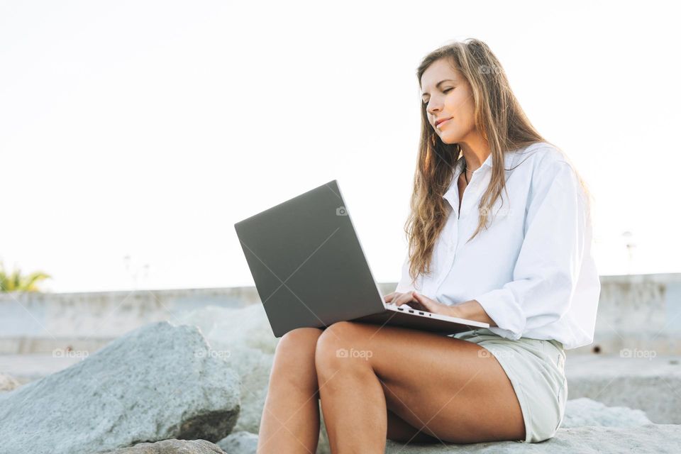 Young woman freelancer with notebook on sea beach